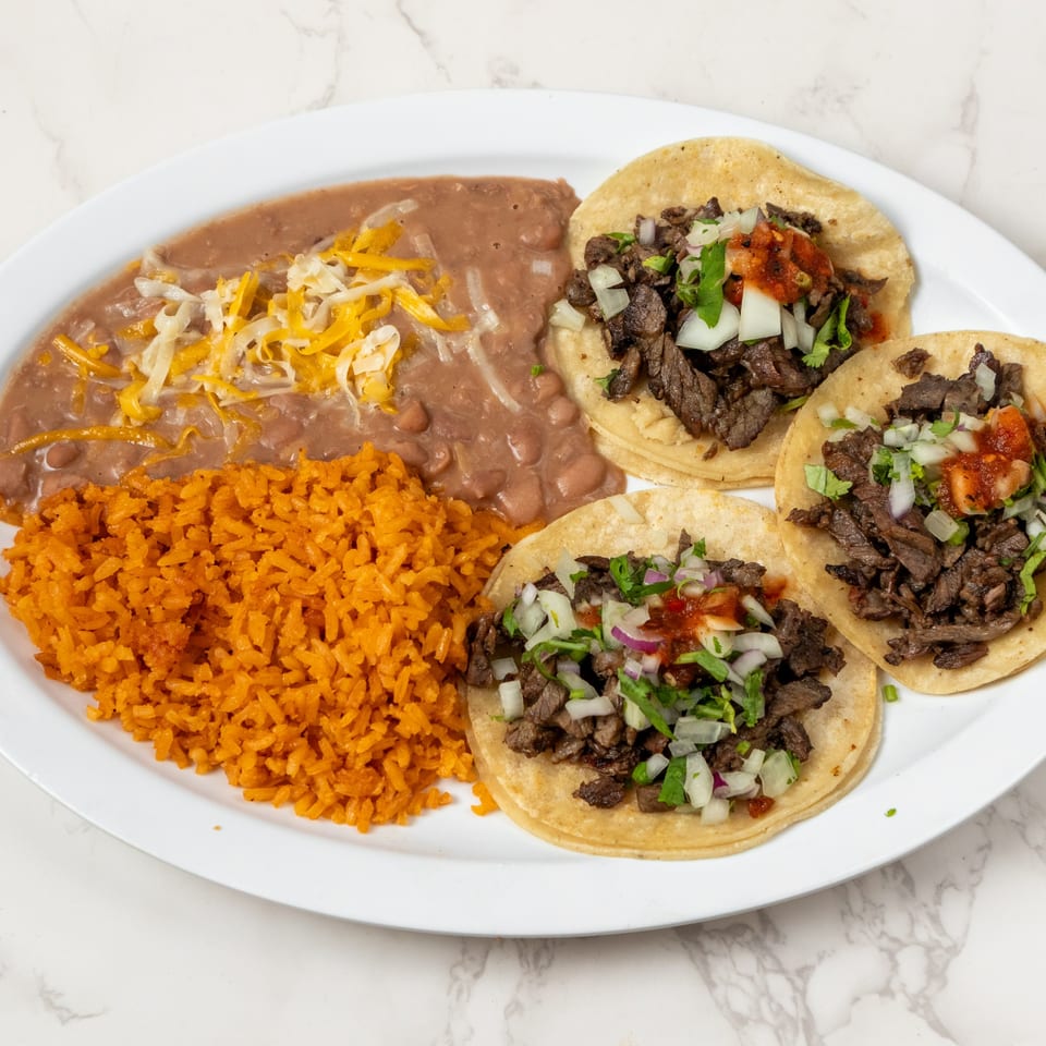 Three beef tacos with cilantro, onions, and salsa, served with refried beans and orange rice.