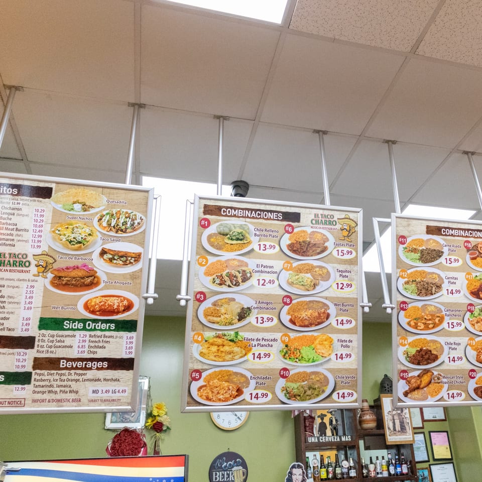 Three large menu boards displaying various Mexican food dishes and prices at El Taco Charro.