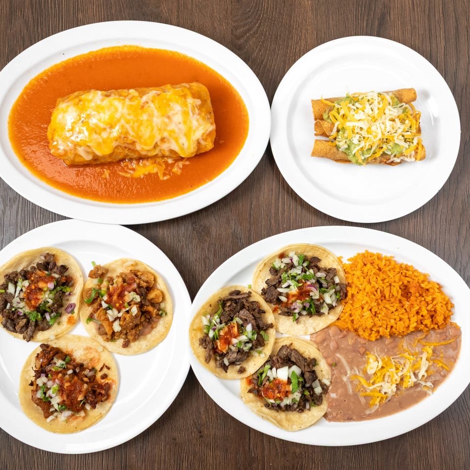 Four plates of Mexican food, including a burrito, taquitos, and various tacos with rice and beans.